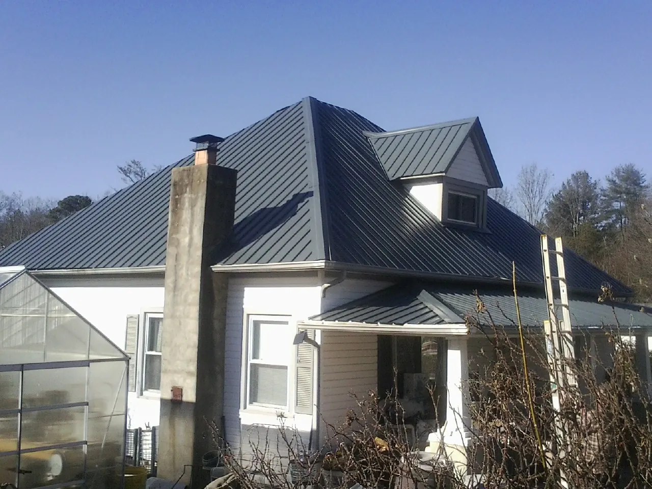 Dark blue standing seam metal roof on a white farmhouse with dormer — Slate & Tile Roof Repair by Roofing Brothers in Rancho Palos Verdes
