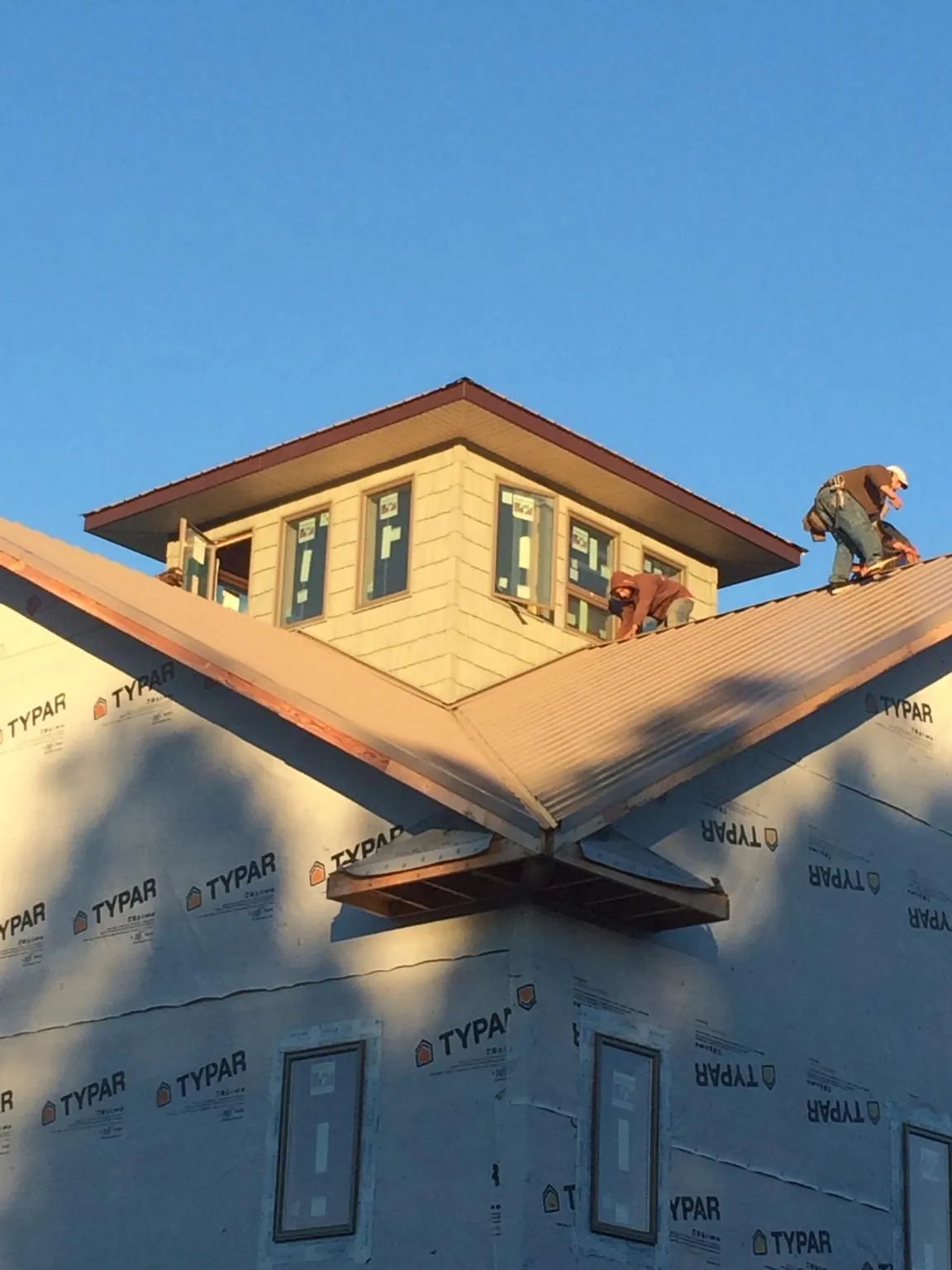 Roofers working around a rooftop cupola on a new metal roof at sunset — Roof Waterproofing in Rancho Palos Verdes by Roofing Brothers